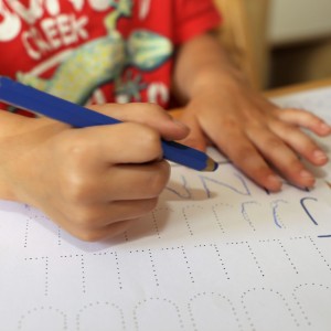 A closeup of a child's hands as he practices writing letters.